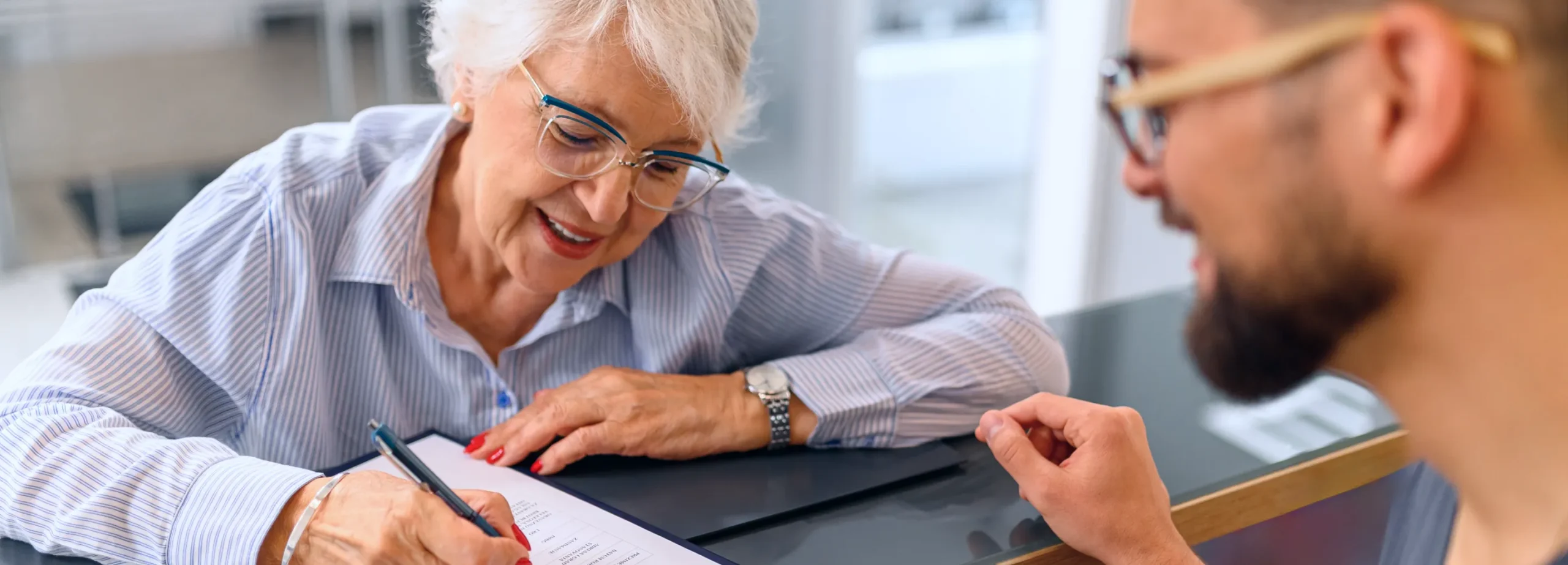 Patient completing healthcare paperwork while speaking with a care coordinator, representing patient acquisition and appointment conversion through targeted outreach
